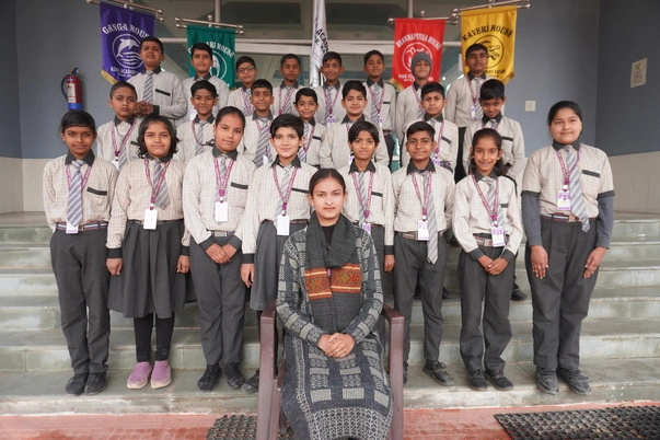 Asha Academy students in uniform posing proudly with their teacher and house flags, representing teamwork and school spirit.