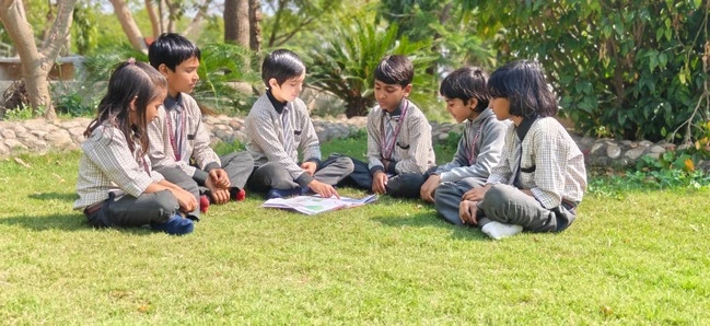 School History whatsapp iGroup of school children sitting on grass outdoors, reading and discussing a book togethermage 2026 02 21 at 13.06.26 (1)